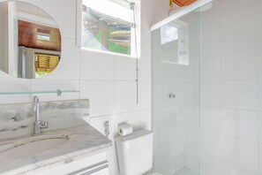 Un bagno con lavabo in marmo, un WC e box doccia in vetro.