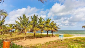 A beach with palm trees and a small blue structure. - IT26 Sea View Bungalow with 3 Suites, Right on the Sand - Varandas do Mar Residential (Camaçari)