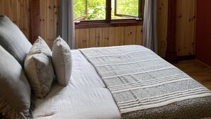 Un dormitorio con cama, almohadas, una ventana con cortinas y un ventilador de techo.