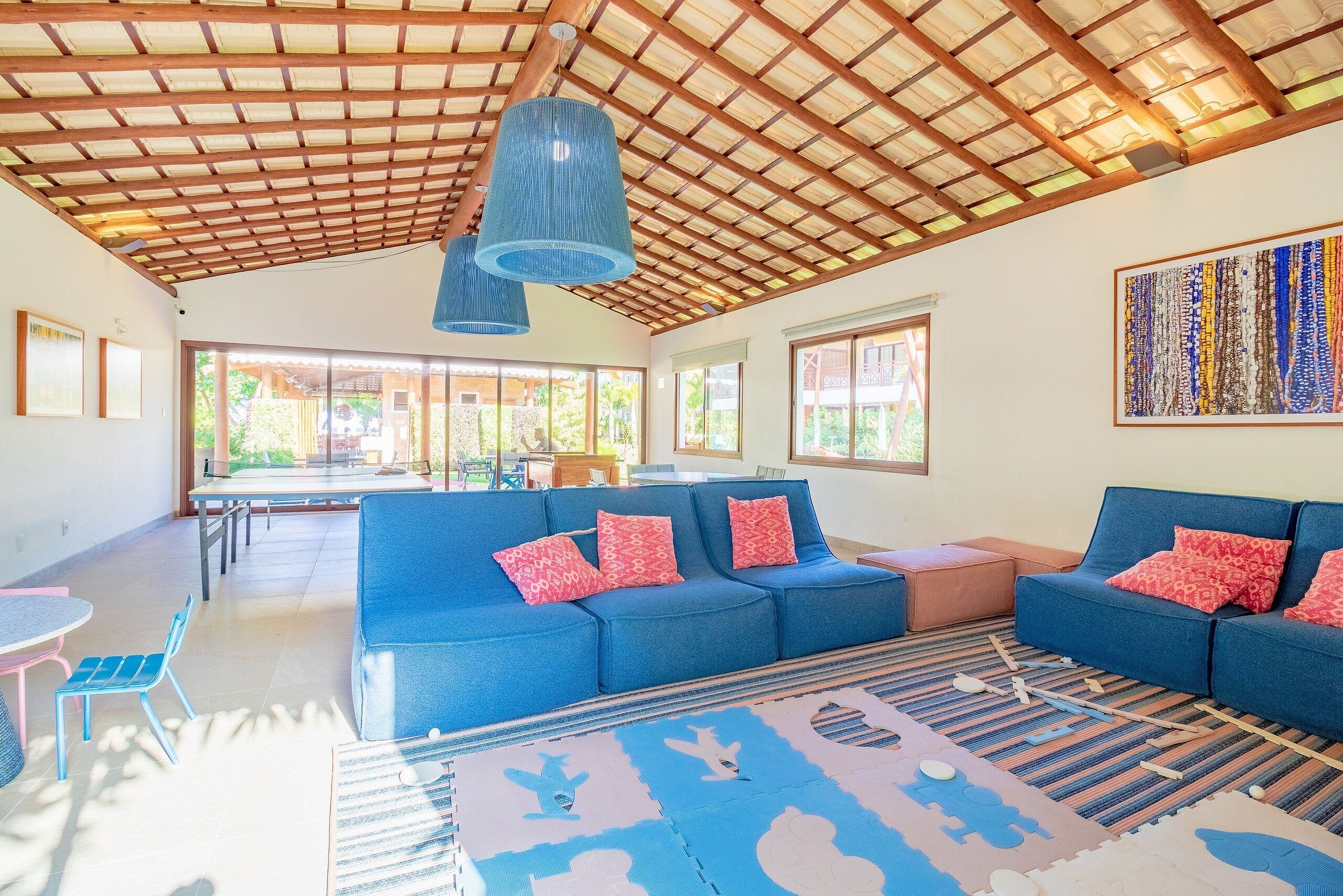 Amplia sala de estar con sofás azules, una mesa de comedor y un ventanal grande.