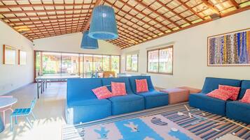 Amplia sala de estar con sofás azules, una mesa de comedor y un ventanal grande.