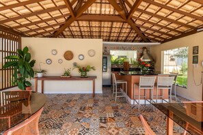 A kitchen with a tiled floor, wooden ceiling, and a bar area with stools.