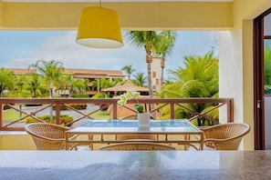 A balcony with wicker furniture, a glass table, and a hanging lamp.