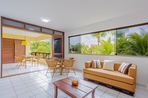 A living room with a sofa, a coffee table, and a dining area with chairs and a table.