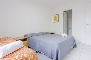 Ein Schlafzimmer mit zwei Betten, einem Nachttisch aus Holz, einer Badezimmertür und einem gerahmten Bild an der Wand.