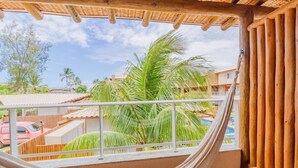 Eine Hängematte auf einem Balkon mit Blick auf Palmen und ein Schwimmbad.