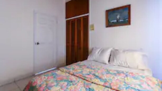Une chambre à coucher avec un lit, une porte et un tableau au mur.