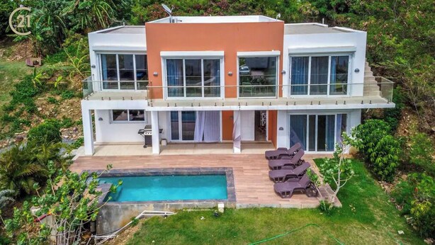 Une maison moderne à deux étages, dotée d’une piscine, de grandes fenêtres et d’un balcon.