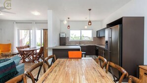Une cuisine moderne avec une table à manger en bois, des meubles de rangement sombres et des appareils électroménagers en acier inoxydable.