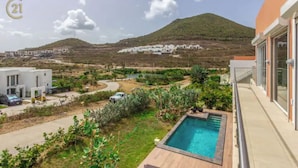 Un quartier résidentiel doté d’une piscine, offrant une vue sur une colline et comprenant un immeuble moderne avec balcon.