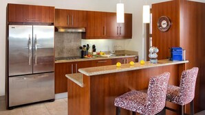 A modern kitchen with wooden cabinets, stainless steel appliances, and a bar area with patterned chairs. - Porto Cupecoy- 3 Bedroom- Luxury Marina Penthouse (Sint Maarten)