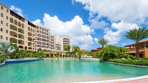 A hotel with a large pool, multiple balconies, and lush greenery. - Porto Cupecoy- 3 Bedroom- Luxury Marina Penthouse (Sint Maarten)
