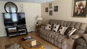 A living room with a television, sofa, coffee table, and decorative wall art. - A & B TRAIL HOUSE @ Hatfield-McCoy Trails, 5 Beds Plus Futon 2 Couches & 2 Baths (DELBARTON)
