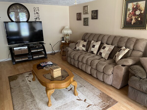 A living room with a television, sofa, coffee table, and decorative wall art.