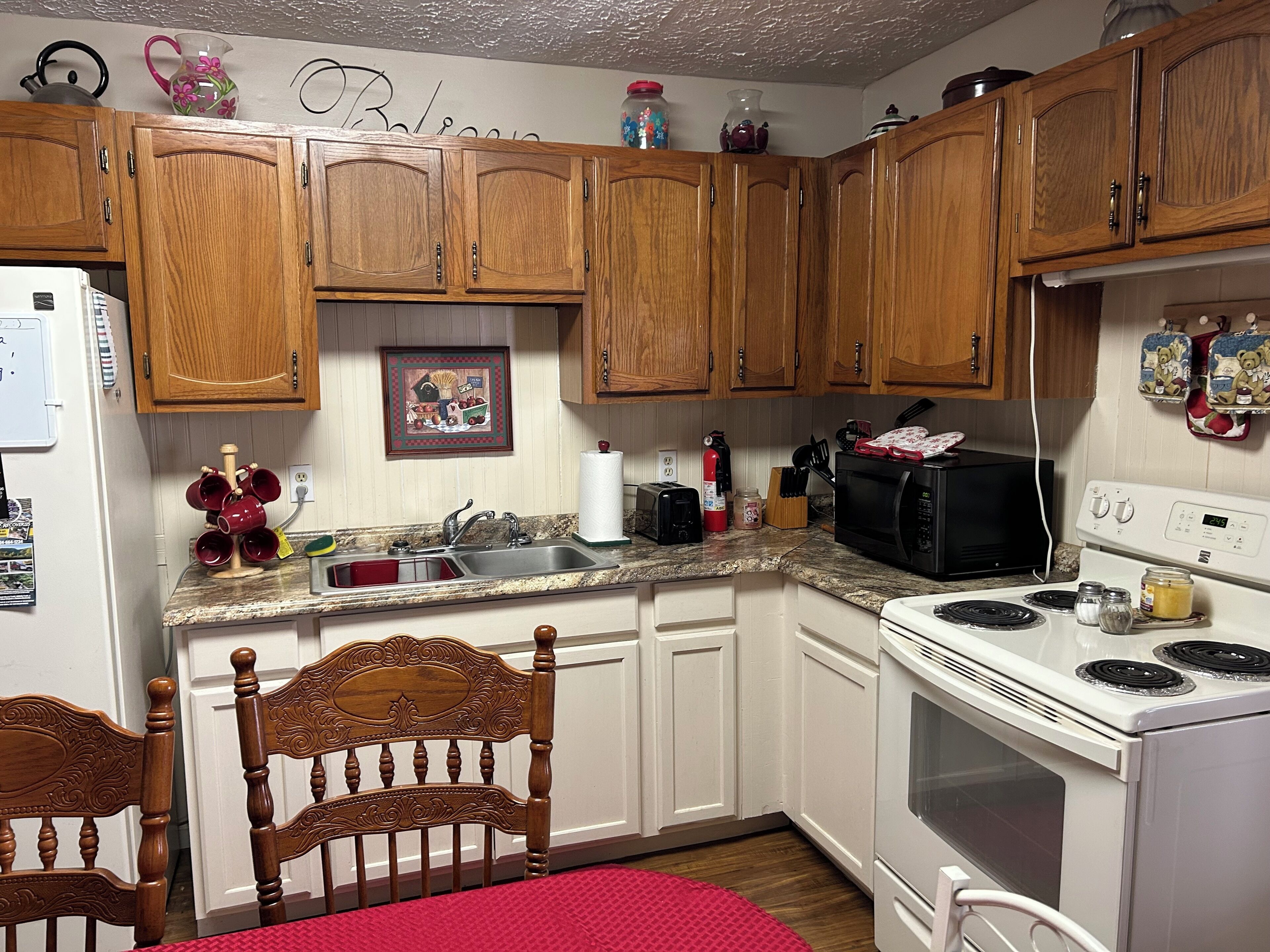 A kitchen with wooden cabinets, a stove, a microwave, and a sink.
