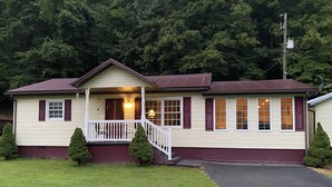 A single-story house with a front porch, a small staircase, and a driveway leading to the front door. - A & B TRAIL HOUSE @ Hatfield-McCoy Trails, 5 Beds Plus Futon 2 Couches & 2 Baths (DELBARTON)