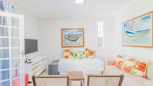 A bedroom with a bed, a TV, a desk, a chair, and a couch.