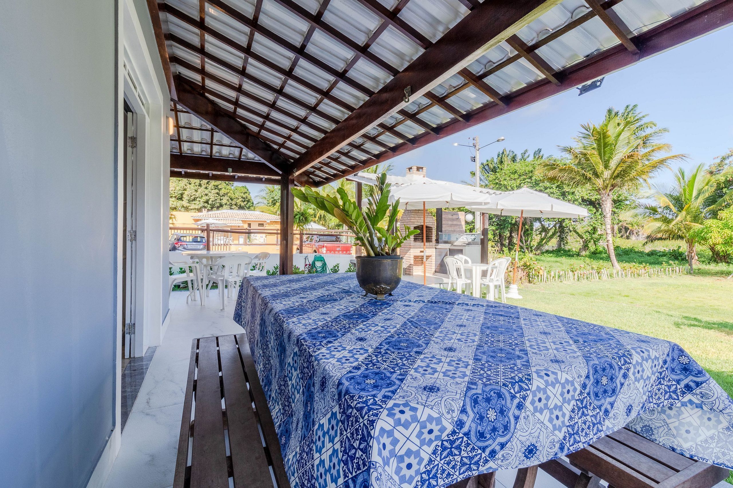 Eine Terrasse im Freien mit einem Tisch, bedeckt mit einer blau gemusterten Tischdecke, umgeben von hölzernen Bänken.
