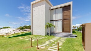 A modern house with a white exterior, a large window, and a well-maintained lawn with stepping stones.