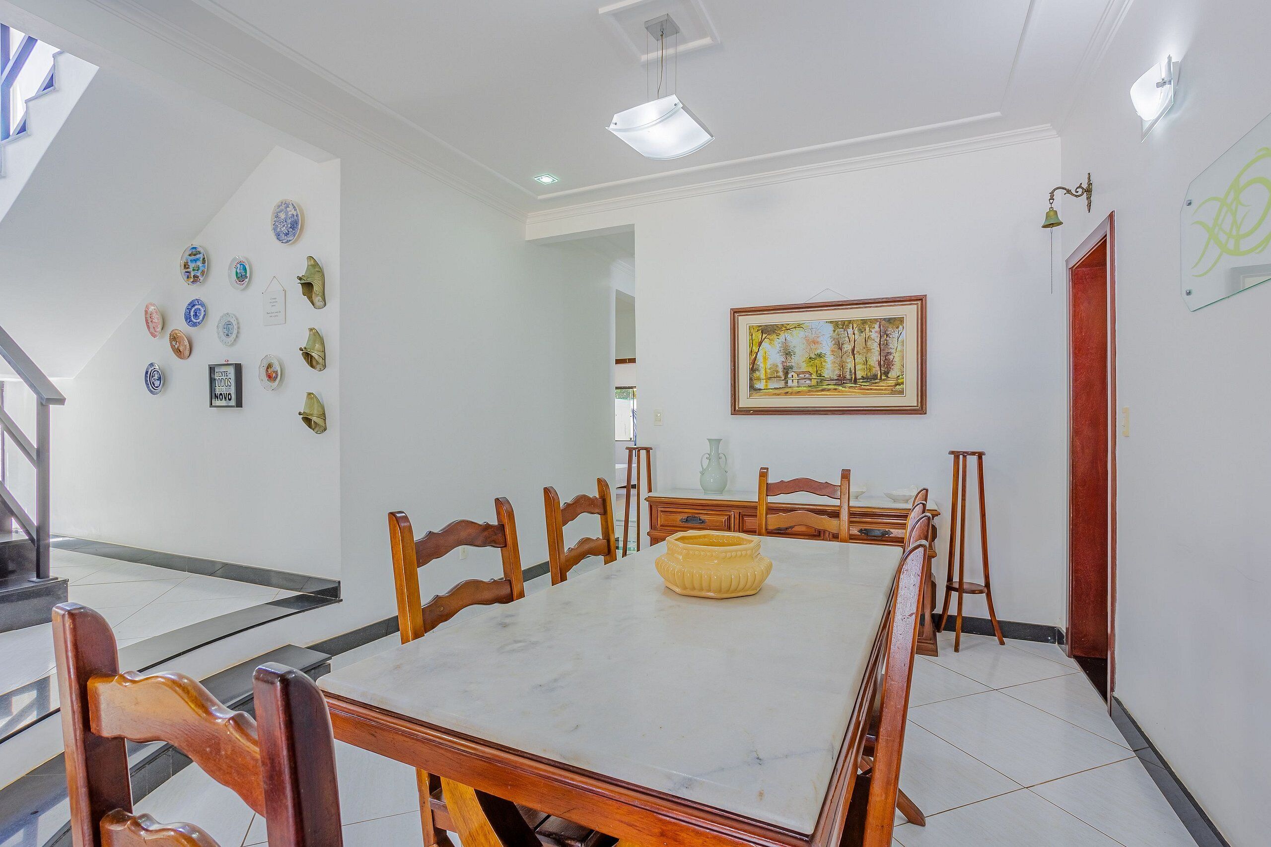 Un coin repas avec une table en marbre, des chaises en bois et une décoration centrale jaune.