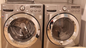 Two front-loading washing machines in a laundry room with light green cabinets above.