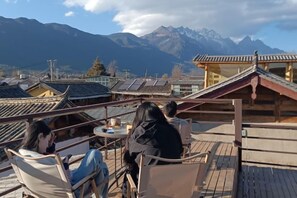 A terrace with chairs and tables overlooking a mountainous landscape. - Ziyou Suiyue Design Hostel (Yulong)