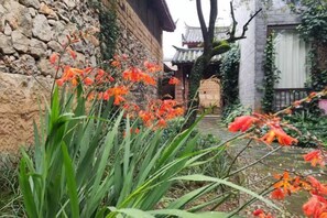 A traditional stone wall with a pathway leading to a building with a tiled roof. - Ziyou Suiyue Design Hostel (Yulong)