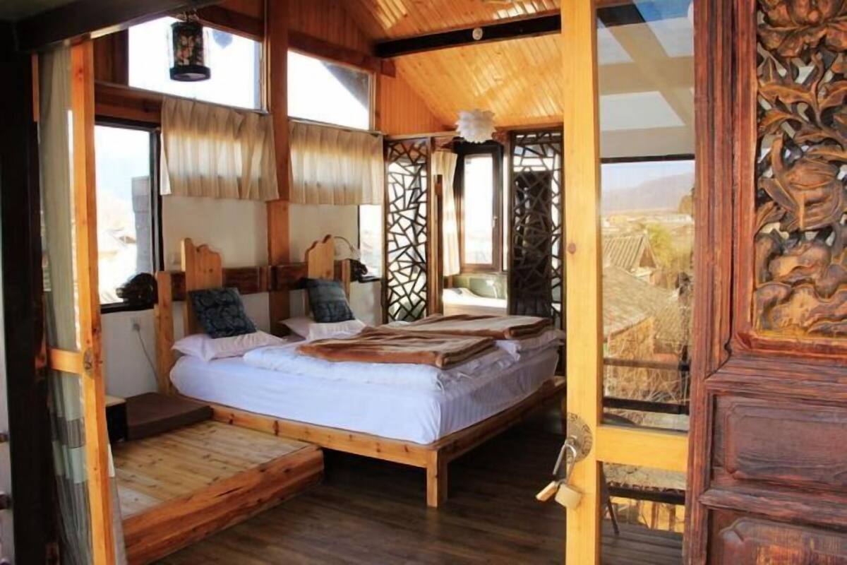 A wooden room with a bed, a window, and a door.