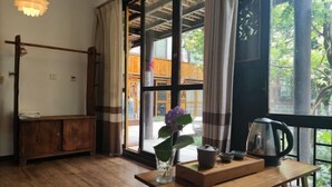 A room with a wooden table, a vase with a flower, a kettle, and a view through a large window. - Ziyou Suiyue Design Hostel (Yulong)