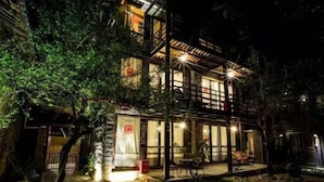 A two-story building with a glass facade, outdoor seating area, and a small garden. - Ziyou Suiyue Design Hostel (Yulong)