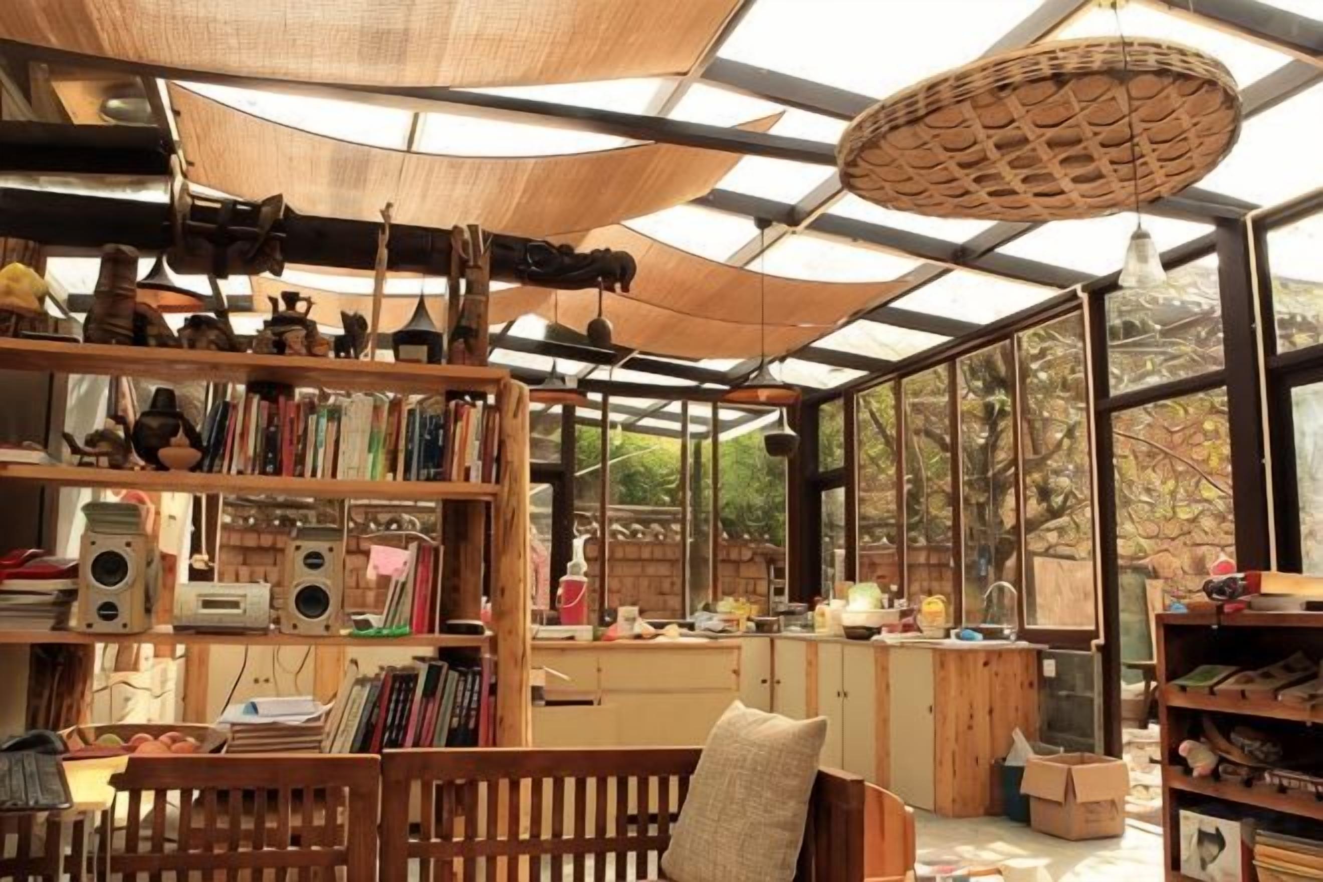 Une pièce dotée d’une grande fenêtre, d’une bibliothèque en bois et d’un luminaire suspendu.