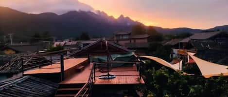 A traditional building with a wooden deck and a view of mountains.