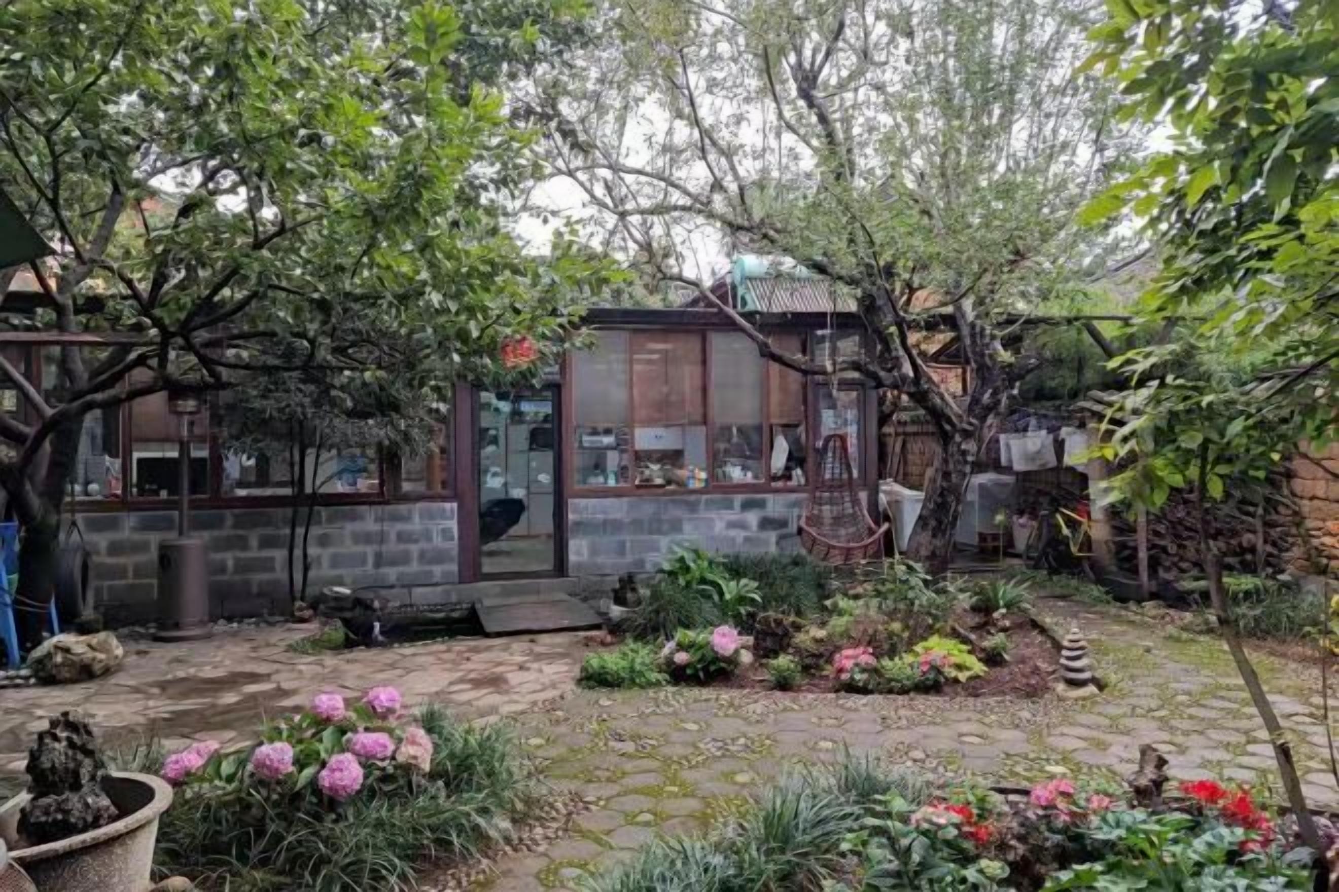 A garden with a stone pathway, potted plants, and a small building with a glass door.
