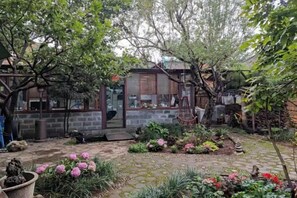 A garden with a stone pathway, potted plants, and a small building with a glass door. - Ziyou Suiyue Design Hostel (Yulong)