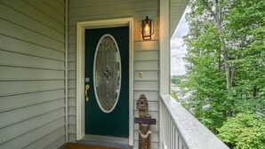 A green door with a glass panel, a welcome mat, a lantern, and a sign on the porch. - Stepping Stone Cove :: Lakefront w/ Dock, Fireplaces & Hot Tub (Mineral)
