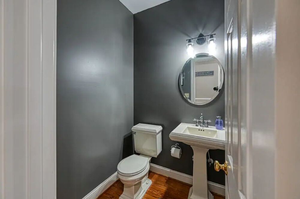 A bathroom with a toilet, sink, and mirror.