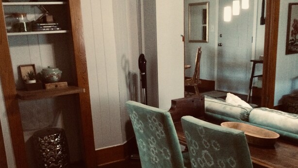 Un comedor con una mesa y sillas de madera, un florero y un espejo en la pared.