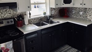 Una cocina con estufa, lavaplatos y armarios.