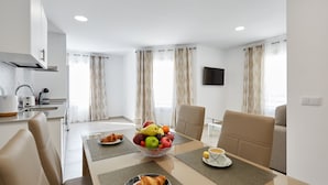 Een moderne hotelkamer met een zithoek, compleet met een ontbijtarrangement: croissants, een schaal fruit en een kop koffie.