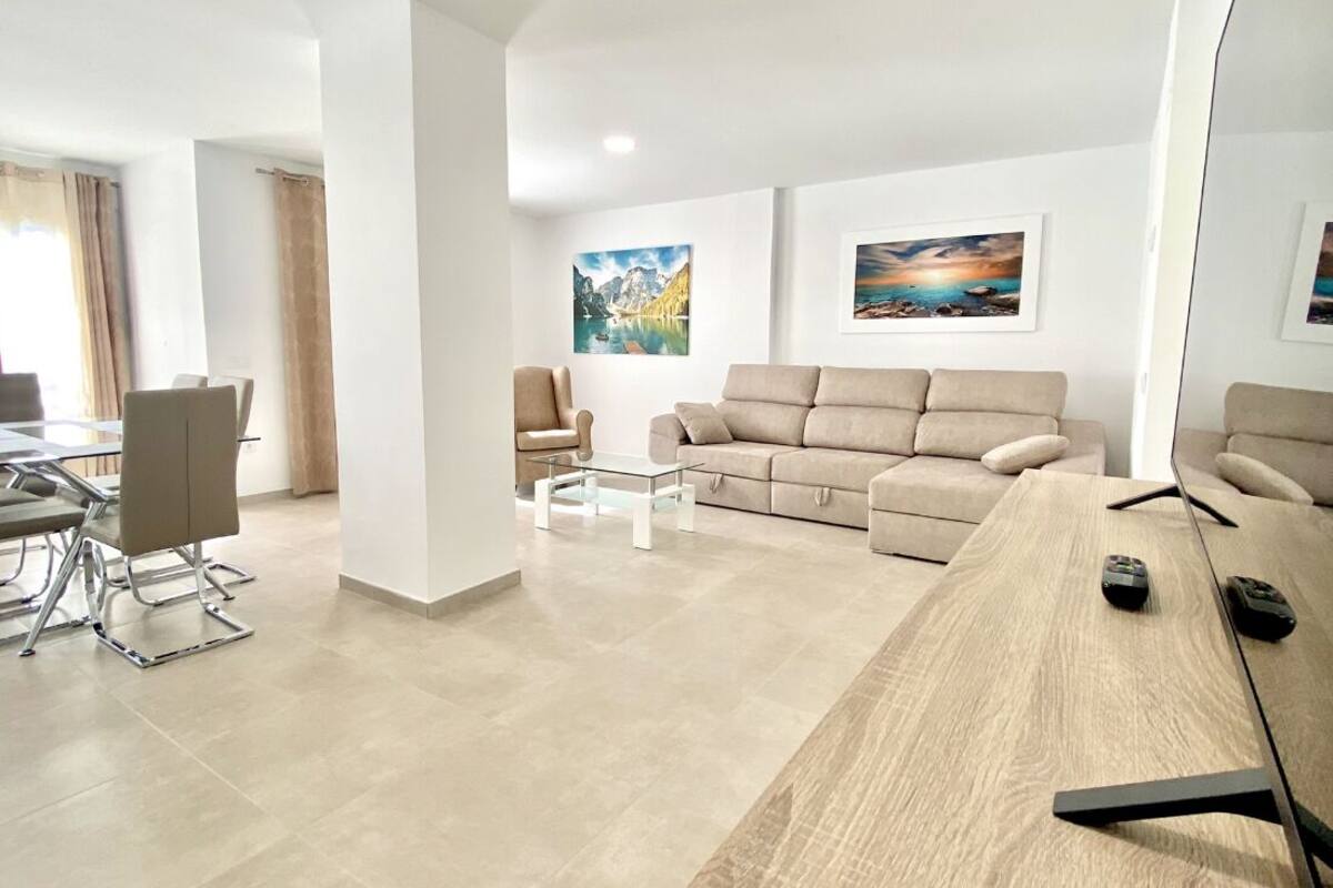Een moderne woonkamer met een bank, een salontafel en een eetgedeelte met stoelen en een tafel.