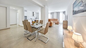 Een modern appartement met een eethoek, keuken, woonkamer en een groot raam.