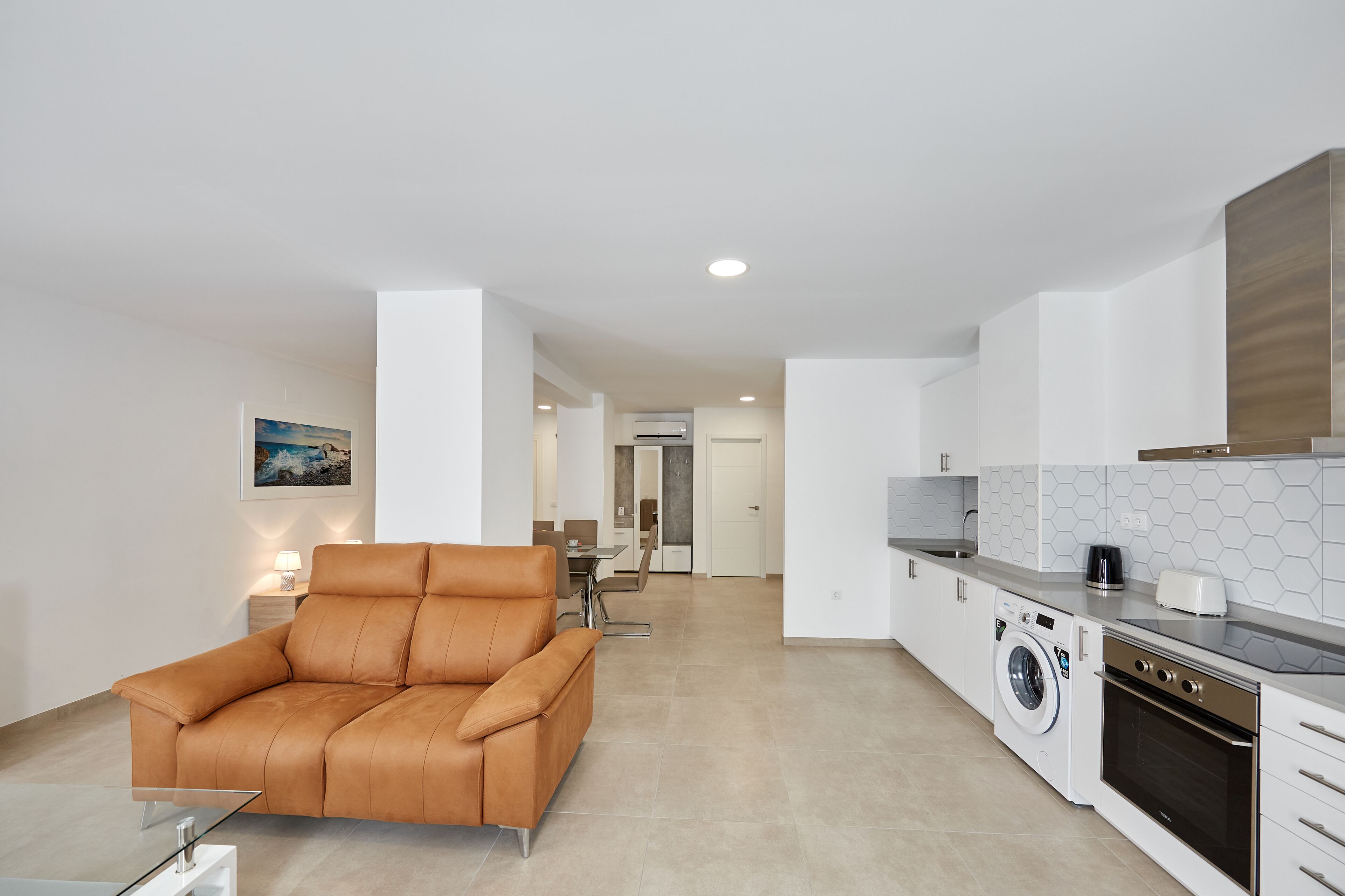 A modern kitchen with a washing machine, oven, and dining area.