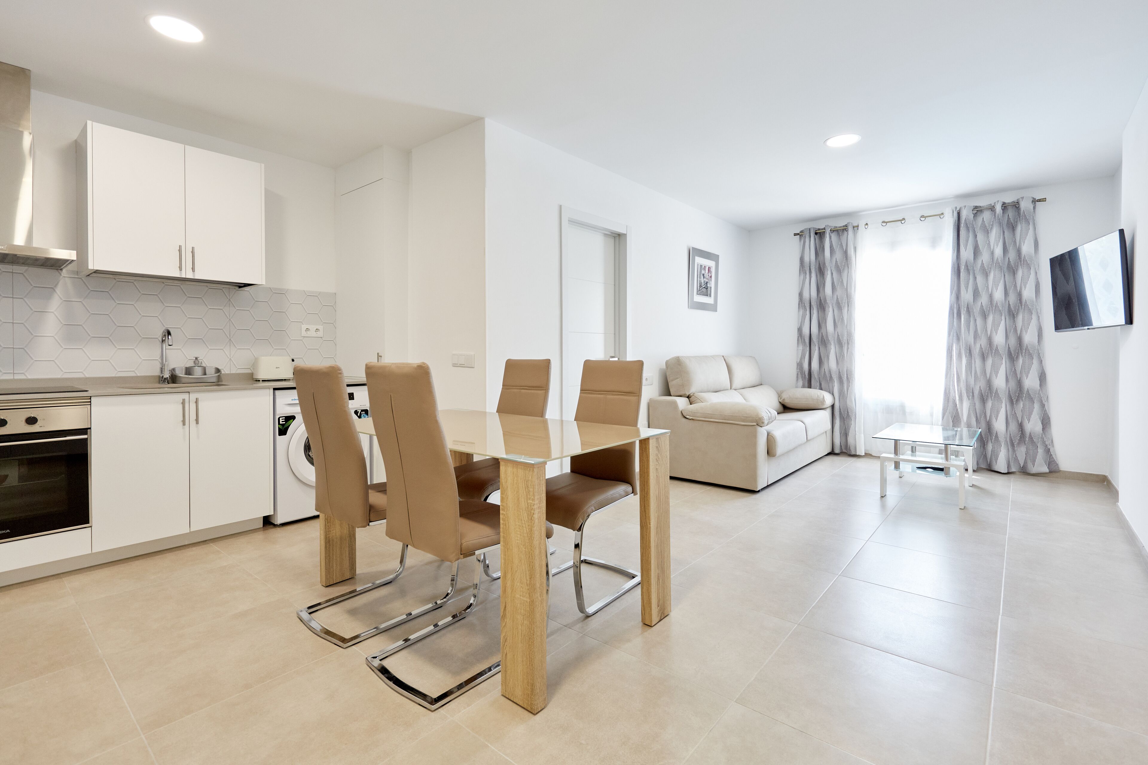 A modern apartment with a dining area, kitchen, and living room.