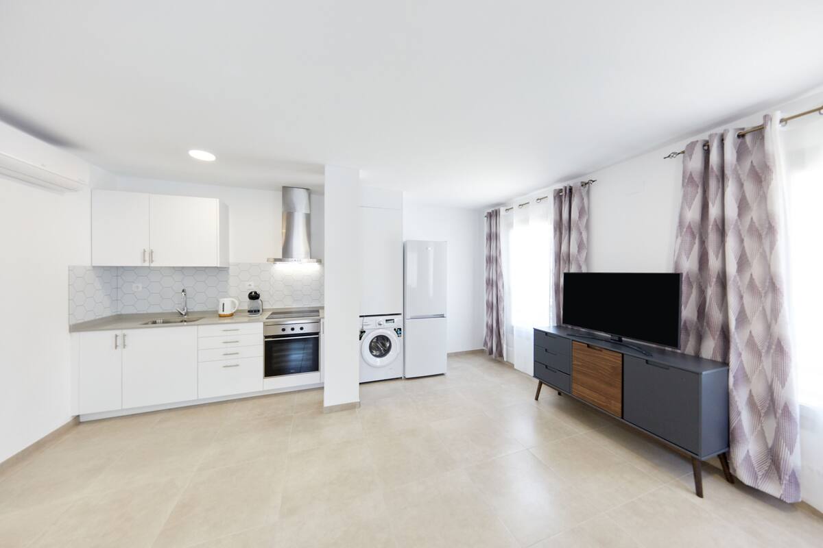 Een moderne keuken met witte kasten, een ingebouwde oven en een wasmachine.