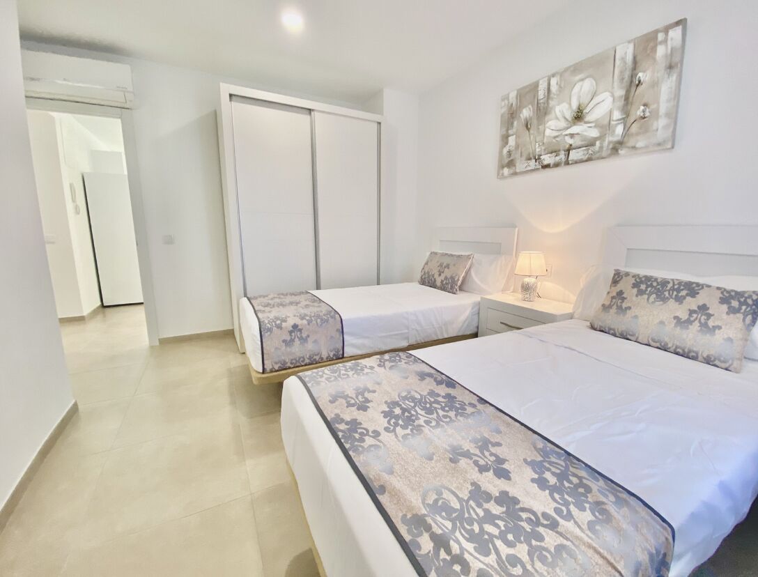A bedroom with two beds, a wardrobe, and a wall-mounted artwork.