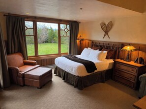 A bedroom with a large bed, a chair, a nightstand, and a view of the outdoors. - 15-45% Off- Whiteface Lodge- Pools, Hot tubs, Spa, Game Room & Theatre! (Lake Placid)