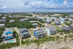 A coastal residential area with houses, some with elevated structures, and a clear view of the ocean.