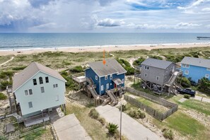 A beachfront property with multiple houses, including a blue house with a red door and a grey house with a blue exterior.