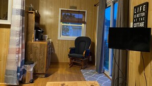 Een knus cabin interieur met houten wanden, een eethoek, een televisie en een raam met uitzicht.