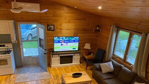 Een gezellig houten interieur met een televisie, een bank en een eettafel.